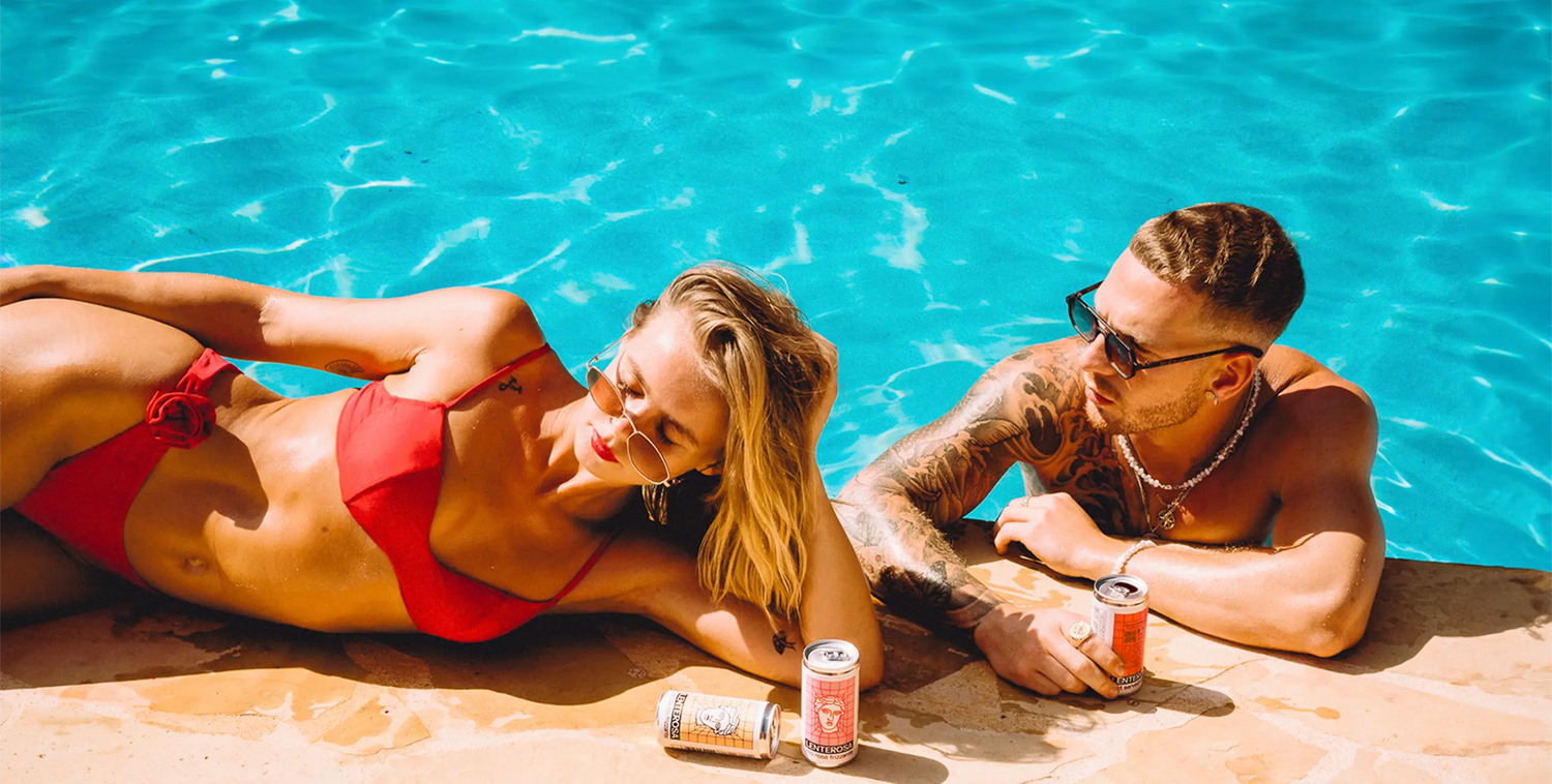 Couple relaxing by the pool with Italian Lenterosa spritz and wine cans